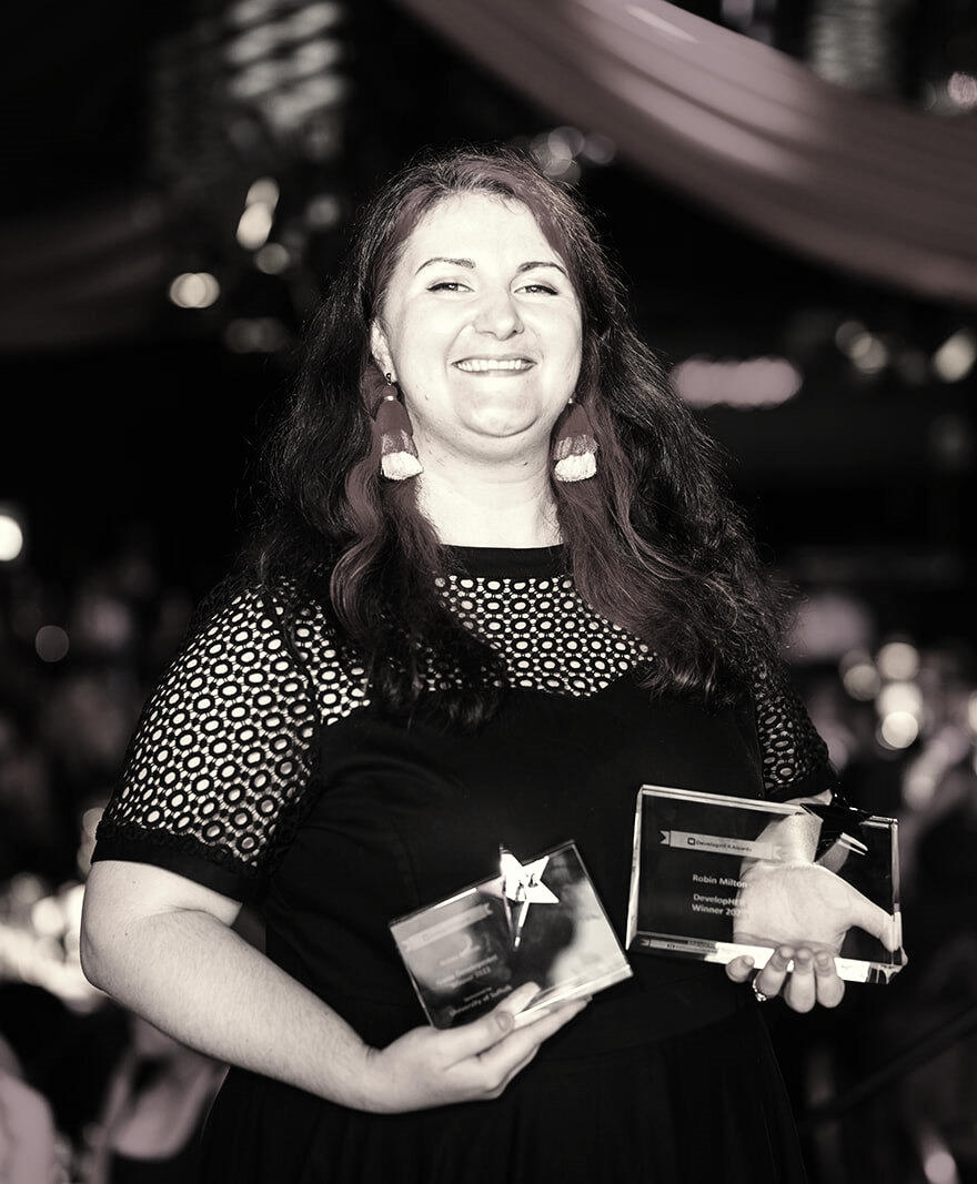 Photograph of Robin Milton at the Develop Her Awards in 2023 holding the two awards she won.
